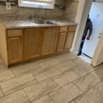 A kitchen with tile floors and wooden cabinets.