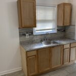 A kitchen with wooden cabinets and marble counter tops.