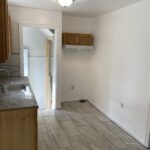 A kitchen with white walls and wooden cabinets.