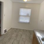 A kitchen with white walls and tile floors.