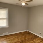 A room with a ceiling fan and wooden floors.