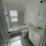 A bathroom with white walls and tile floors.