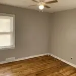 A room with a ceiling fan and wooden floors.