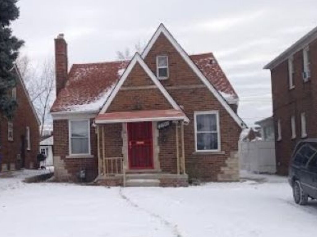 Brick house with red door in snow.