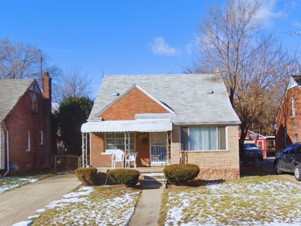 Small brick bungalow with front porch and shrubs