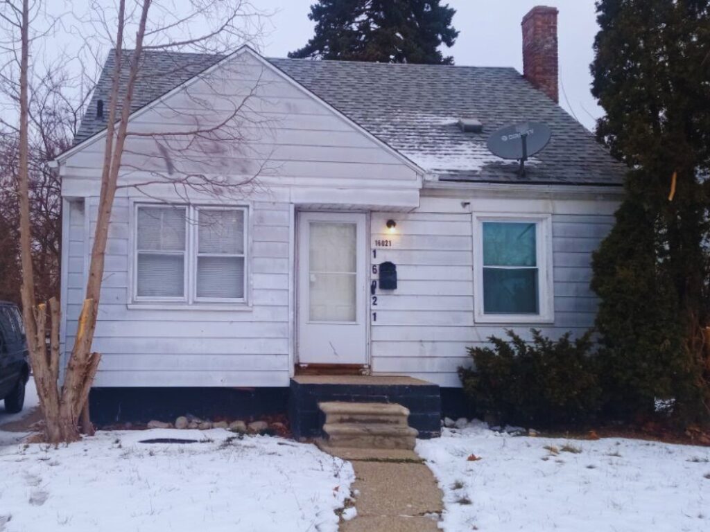 Small white house with snowy yard.