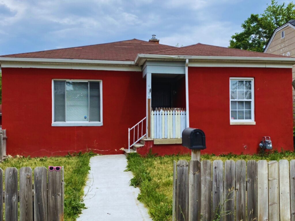 Red house with white fence and pathway.