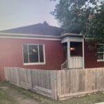 Red brick house with wooden fence.
