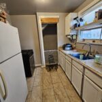 Narrow kitchen with white cabinets and appliances.