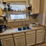 Small kitchen with white cabinets and sink.