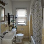 Small vintage bathroom with shower and sink.