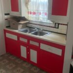Red kitchen cabinets with a double sink.