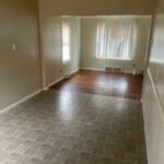 Empty room with tiled and wooden flooring.