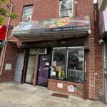 Brick storefront with signs and open door.